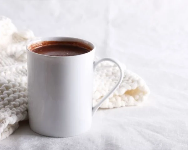 A mug of dark hot chocolate. The hot chocolate is the focal point of the image.
