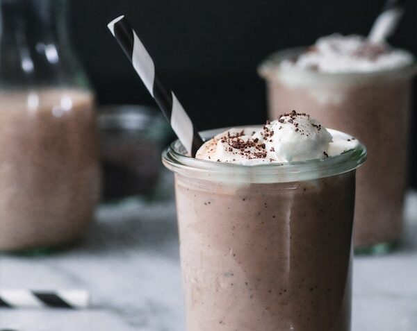 Three chocolate milkshakes with cream and straws