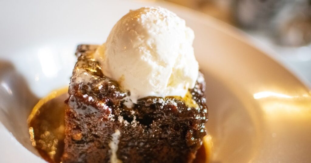 Close up of sticky toffee cake with ice cream on top