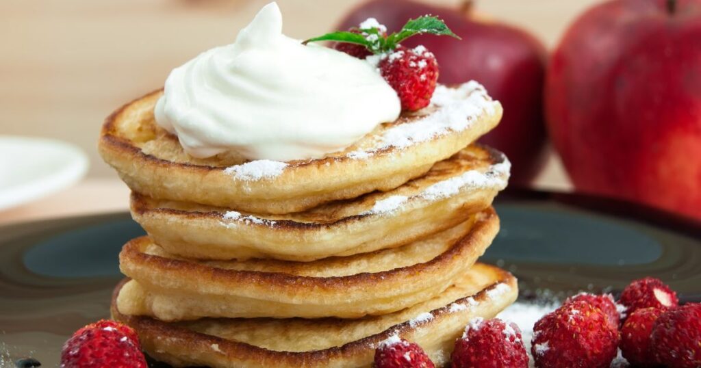 A stack of pancakes with cream fraiche and berries