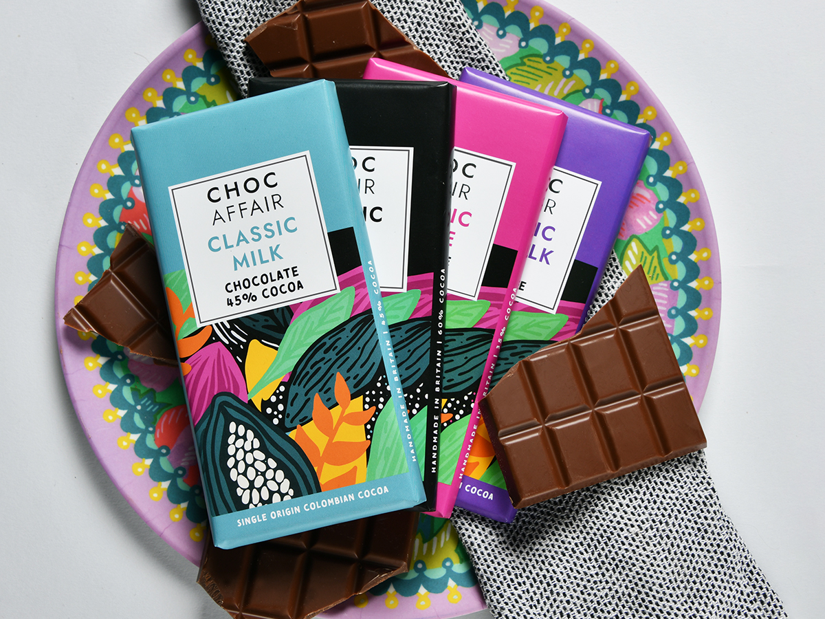 Selection of milk, dark and white chocolate bars displayed with chocolate pieces on a decorative plate